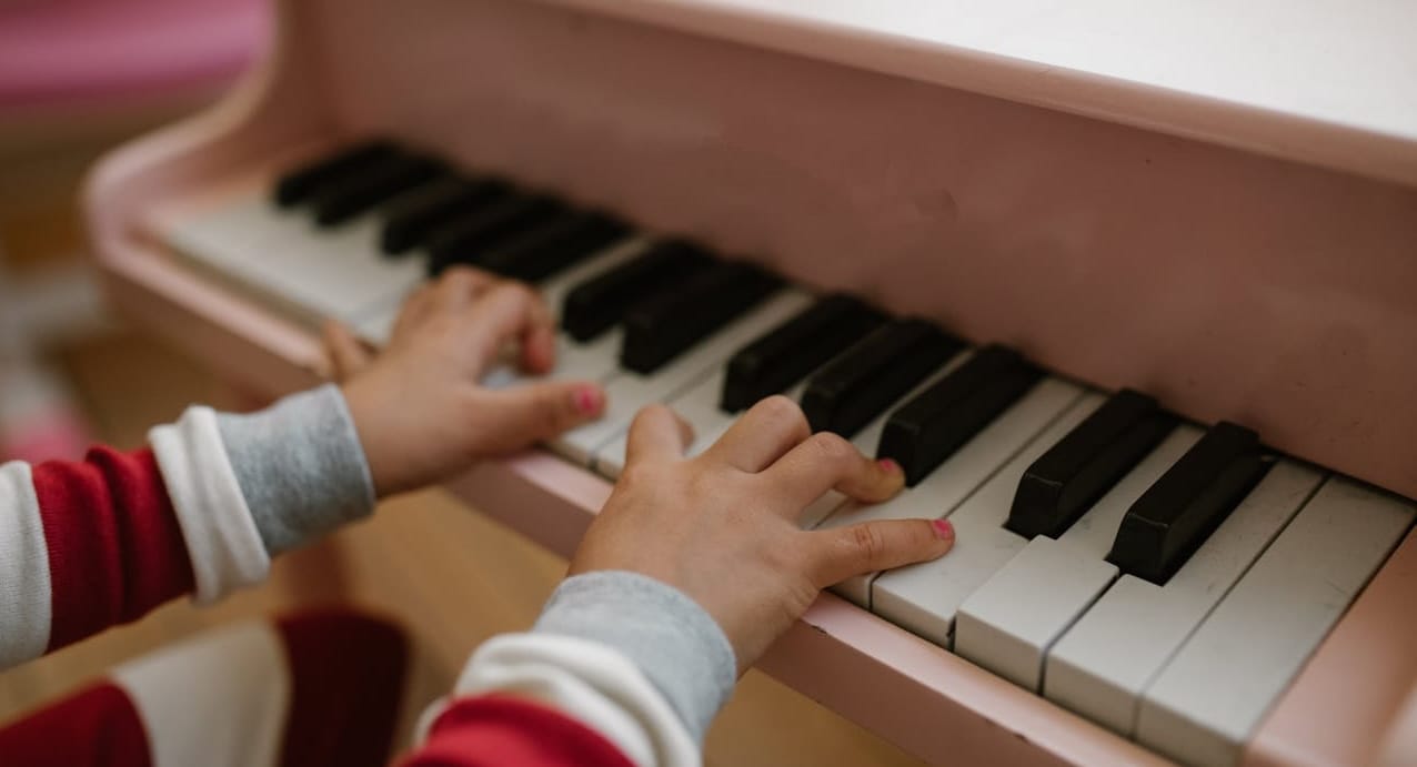 A child's hands playing a toy piano.