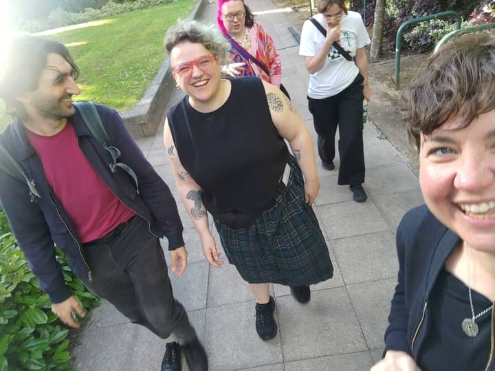 5 happy humans walking on a path in the sunshine and smiling at the camera